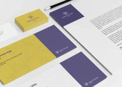 Como parte del diseño de identidad visual se diseñó la papelería, que está integrada por: hoja membreteada, los sobres y las tarjetas de presentación. La hoja membreteada tiene el logotipo en color gris sobre un rectángulo color morado sabio. En la carta se utiliza la tipografía Open Sans, en la parte inferior de la hoja se encuentran los datos de contacto y la dirección de la escuela. Se proponen dos versiones de sobres: la primer opción de sobre tiene una franja gruesa del lado derecho color morado con el logotipo en su versión horizontal, pequeño en la parte inferior del rectángulo. El área restante es color ocre con una textura formada por los elementos gráficos (Buda, piedras en equilibrio, flor de loto, gota de agua y cuenco). Los datos de la escuela se encuentran en la parte superior izquierda del sobre. La segunda propuesta es igual, pero sin el color ocre y la textura de los elementos que acompañan a la marca. Las tarjetas de presentación son de doble vista, por un lado el fondo es color ocre y el logotipo en su versión vertical en color morado. En el lado opuesto vienen los datos de contacto y en la parte superior se usa el símbolo del logotipo en repetición para formar una textura lineal.