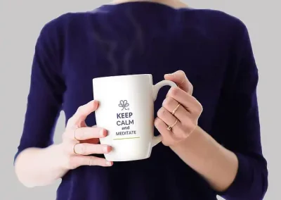 Ejemplo de diseño de identidad visual: en la imagen se muestra una taza blanca con isotipo y leyenda “Keep calm and meditate” con tipografía Artico Soft, todo de color morado sabio. Hasta abajo se colocó una franja delgada color ocre.